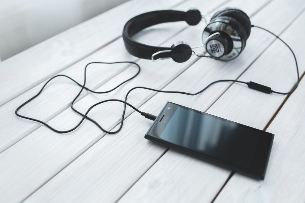 black smartphone and headphones on a desk